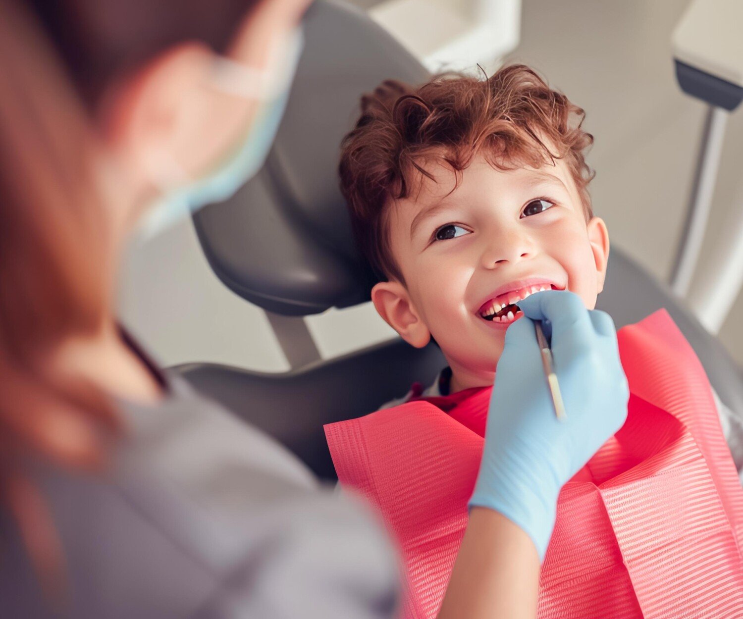 child sitting in a dental chair with a dentist examining their teeth.